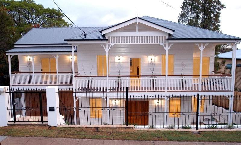 Restored white Queenslander home with wraparound verandahs at dusk